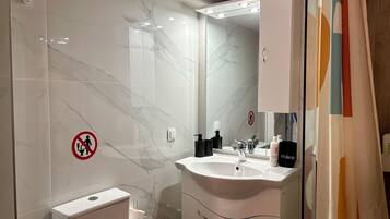 Une salle de bain avec un mur en marbre, un lavabo, des toilettes et une douche.
