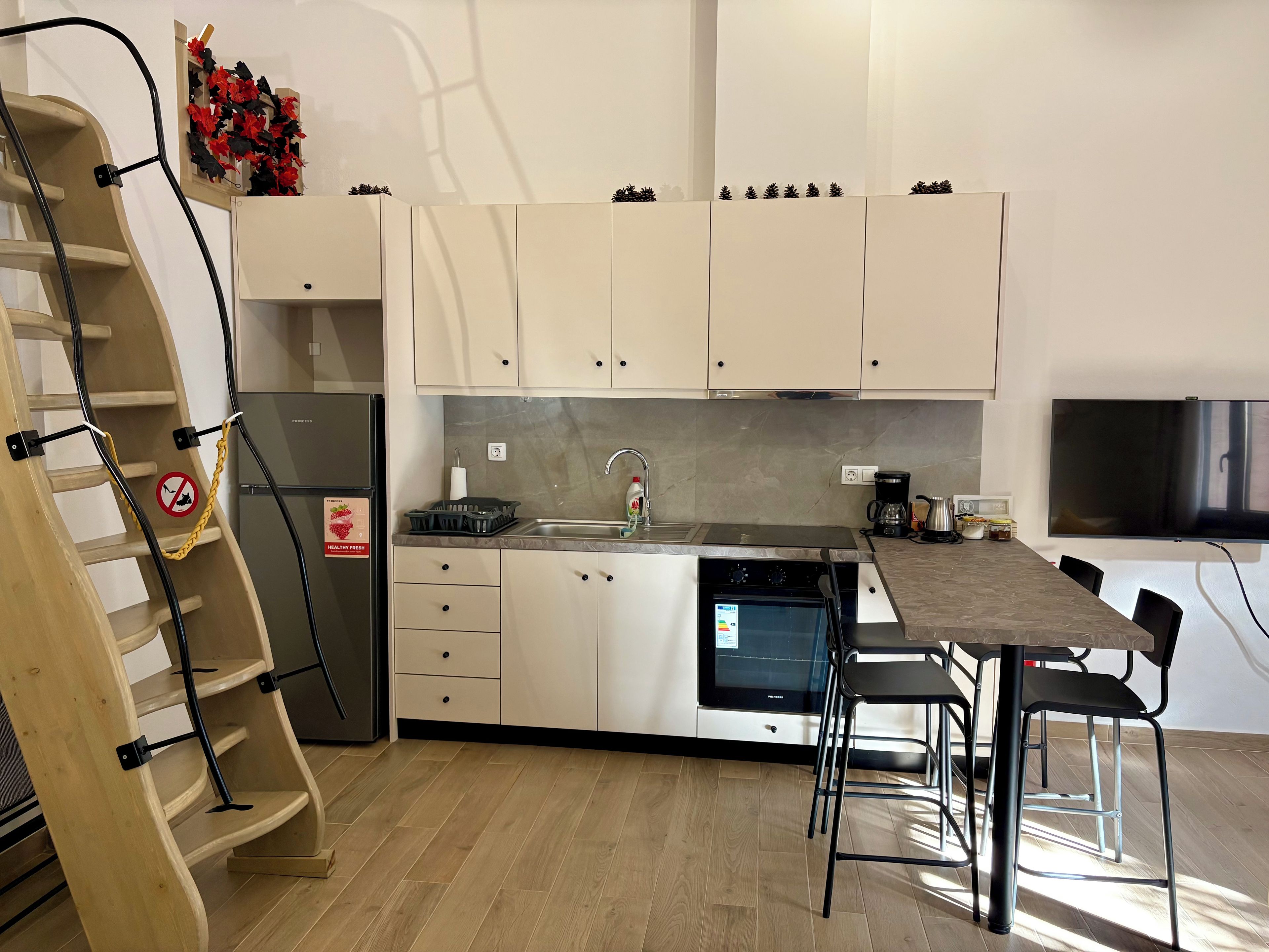 A modern kitchen with white cabinets, a built-in oven, a stainless steel sink, and a dining area with a table and chairs.