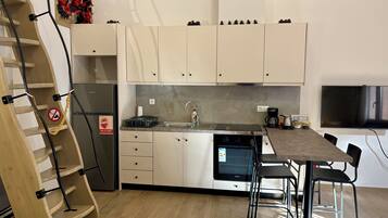 A modern kitchen with white cabinets, a built-in oven, a stainless steel sink, and a dining area with a table and chairs.
