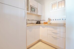 A modern kitchen with white cabinetry, a built-in oven, and a coffee maker on the countertop. - New Listing (Benalmádena)