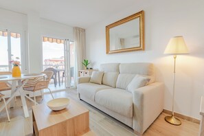 A modern living room with a sofa, a dining table with chairs, a floor lamp, and a large mirror on the wall. - New Listing (Benalmádena)