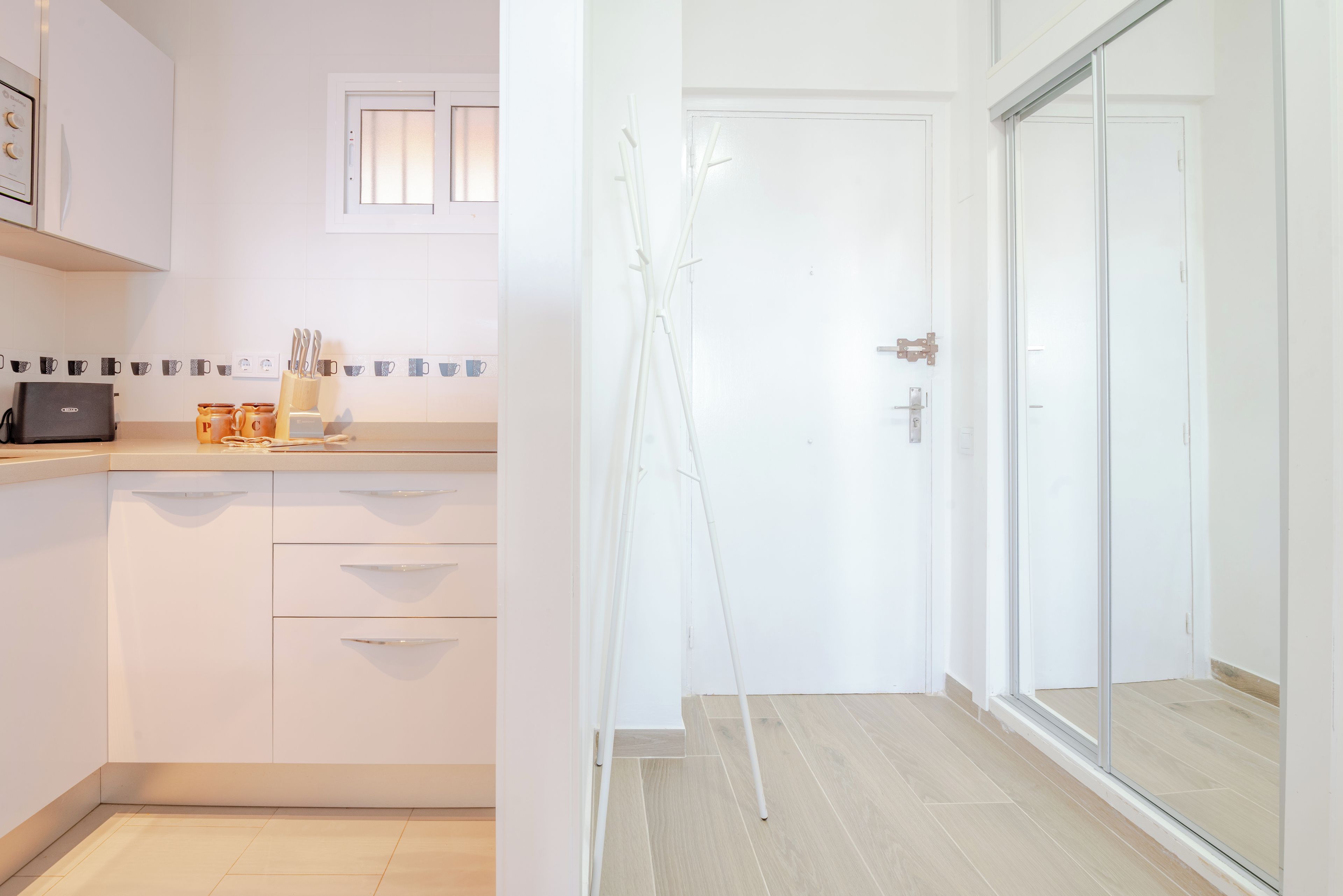 A modern kitchen with white cabinets, a coffee machine, and a window.