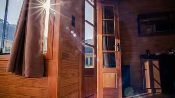 Un interior de madera con un gran ventanal, una puerta y una zona de cocina.