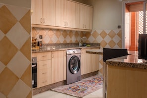 A compact kitchen with a washing machine, a sink, and a countertop with various items. - Marrakech 2 Bedroom 2 Bathroom Luxury Apartment,Large Balconies and Free Parking (Marrakech)