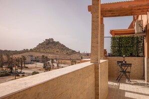 A balcony with a view of a hilltop building, a table with chairs, and a potted plant. - Marrakech 2 Bedroom 2 Bathroom Luxury Apartment,Large Balconies and Free Parking (Marrakech)