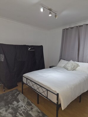 Un dormitorio con cama, cortinas, cabecero y lámpara en el techo.