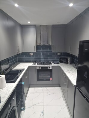 A modern kitchen with grey cabinets, a stainless steel range, a built-in oven, and a black refrigerator. - Welcome to Your Stylish East London Getaway!
Newly renovated from top to bottom (Barking)
