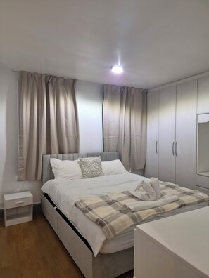 A bedroom with a bed, a nightstand, a wardrobe, and a mirror. - Welcome to Your Stylish East London Getaway!
Newly renovated from top to bottom (Barking)