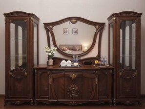 A wooden dresser with a mirror, a vase with flowers, and toiletries. - Heart of Baku: Targovi Apartment with Stunning Boulevard View (Baku)