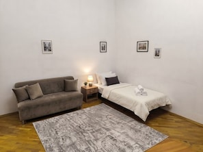 A bedroom with a sofa, a bed, a nightstand with a lamp, and a rug. - Heart of Baku: Targovi Apartment with Stunning Boulevard View (Baku)
