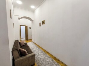 A hallway with a sofa, a patterned rug, and a door leading to another room. - Heart of Baku: Targovi Apartment with Stunning Boulevard View (Baku)