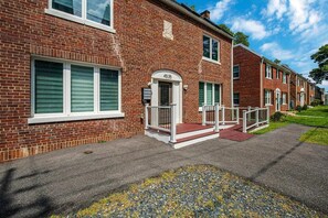 A red brick residential building with a white-framed entrance, a small porch, and a clear sky. - 1.2 Miles to NIH & Walter Reed - Walk to Metro (Bethesda)