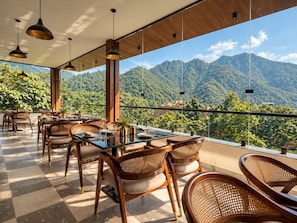 Un restaurante con terraza y vistas a un paisaje montañoso.