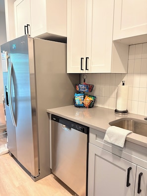 A kitchen with a stainless steel refrigerator, a dishwasher, and a sink with a towel. - Elevated Luxury apartment in Downtown Jacksonville (Jacksonville)