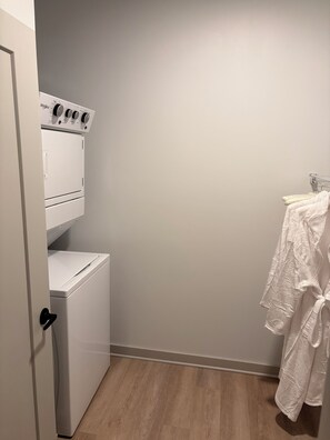 A laundry room with a front-loading washer and dryer, a wooden floor, and a towel rack with a white towel. - Elevated Luxury apartment in Downtown Jacksonville (Jacksonville)