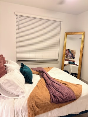 A neatly made bed with a white comforter, a brown blanket, and a blue pillow. - Elevated Luxury apartment in Downtown Jacksonville (Jacksonville)