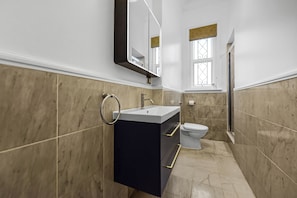 A bathroom with a sink, toilet, and shower. - Three Bedroom Hampstead Apartment (London)