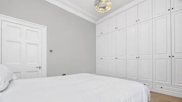 Un dormitorio con una cama grande, un armario blanco y una araña.