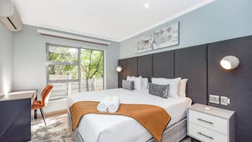 Une chambre d’hôtel moderne, dotée d’un grand lit, de tables de chevet, d’un bureau et d’une chaise.