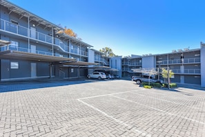A multi-story parking garage with several cars parked, a covered walkway, and a clear blue sky. - Luxury 2Bed Retreat Sandton With Free Parking (Sandton)