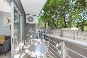 Ein Balkon mit Tisch und Stühlen, eine Glastür und eine Wand-Klimaanlage.