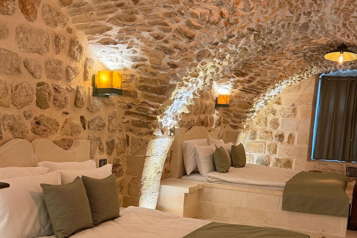 Habitación de paredes de piedra con una cama, zona de estar y una ventana.