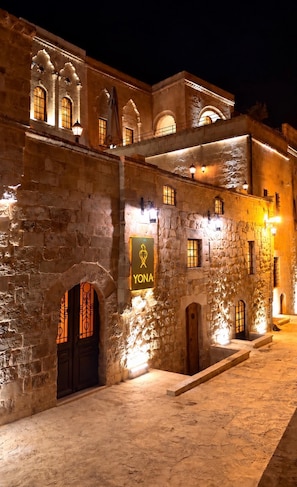 A stone building with arched windows and a sign reading 'YONA'. - YONA OTEL (ARTUKLU)