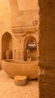 A stone-walled room with a large basin, a small pot, and a wall-mounted fixture.