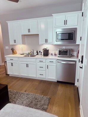 A modern kitchen with white cabinetry, a built-in microwave, a toaster oven, and a dishwasher. - Cozy 1-bedroom apartment in perfect Winchester with AC (Winchester)