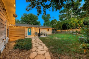 A stone pathway leading to a wooden house with a stone exterior and a blue door. - Remodeled 2BR | Near Mueller, UT & Downtown (Austin)
