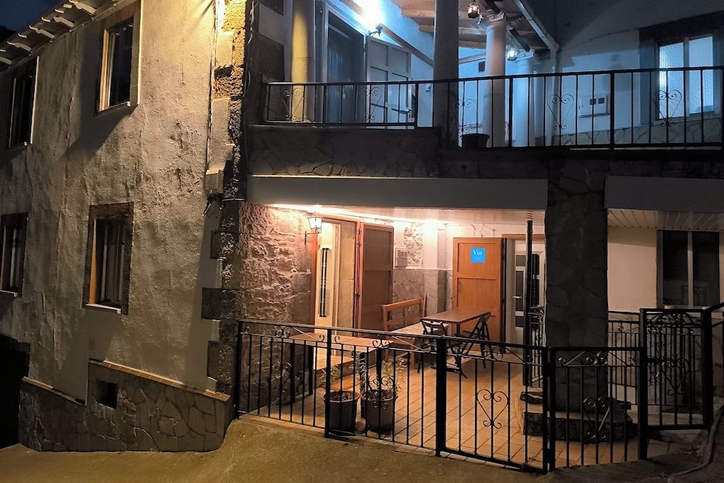 Un bâtiment à deux étages doté d’un balcon, d’un coin repas avec une table et des chaises, et d’un escalier menant à l’étage supérieur.