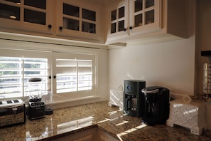 A kitchen with a granite countertop, a coffee maker, a toaster, and a blender. - Luxury Warm Modern Retreat in Utica Square w/ 2 King Suites, 3 Patios & Spa Bath (Tulsa)