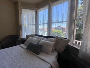 Una camera da letto con un letto, una sedia e vista all'esterno tramite ampie finestre.