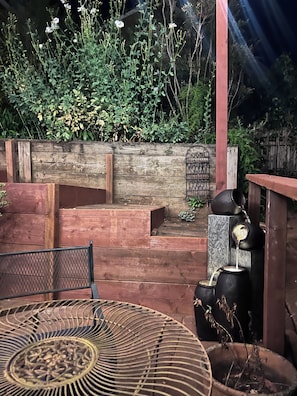 A garden with a wooden bench, a metal table, and a water feature. - Easy SF Access from Spacious apartment in Sausalito with stunning views (Sausalito)