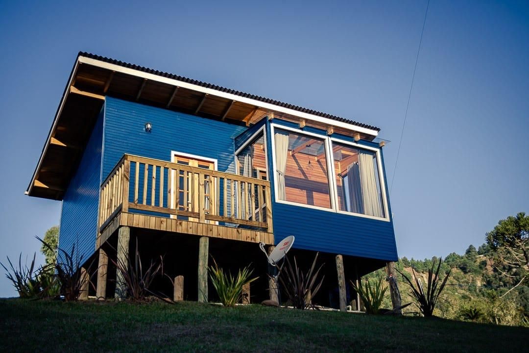Una casa de dos pisos con terraza de madera, ventanas grandes y una antena parabólica.