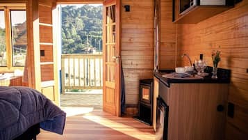 Un interior de madera con una cama, una zona de cocina y vistas al exterior.