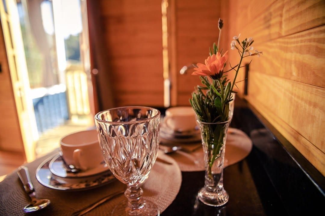 Ein Tisch gedeckt mit einem Glas, einer Tasse und einer Vase mit Blumen.