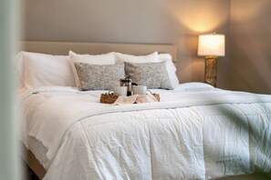 A neatly made bed with a white duvet, two pillows, a coffee maker, and two cups on a woven tray. - 6 Country Club Rd (Cocoa Beach)