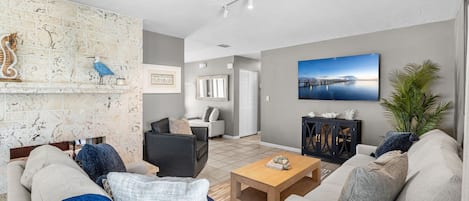 A modern living room with a fireplace, a large painting, and a view of a pier.