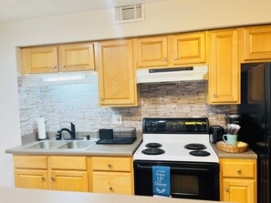 Una cocina con armarios de madera, salpicadero de piedra, estufa y refrigerador.
