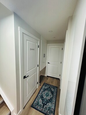 A hallway with white doors, one labeled 'LAUNDRY,' and a patterned rug on the floor. - Sheen’s Suite-Walkout Basement with Scenic Views (Calgary)