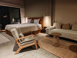 Ein Schlafzimmer mit einem Bett, einem Holzstuhl, einem kleinen Tisch und einem Sofa.