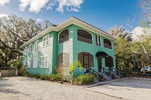 Un edificio a due piani con facciata verde, numerose finestre e un ingresso principale con una scala.