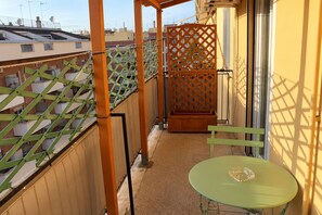 A balcony with a green table and chairs, a wooden planter, and a lattice partition. - New Listing (Roma)