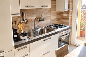 A modern kitchen with a gas stove, stainless steel sink, and wooden backsplash. - New Listing (Roma)