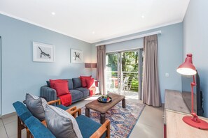 A modern living room with a sofa, two armchairs, a coffee table, and a red floor lamp. - Luxury 2Bed Apartment  Minutes from Sandton (Sandton)