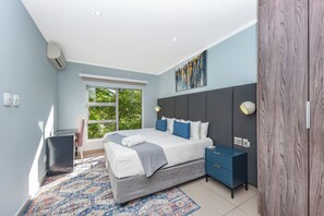A modern bedroom with a large bed, bedside tables, a wardrobe, and a window with a view. - Luxury 2Bed Apartment  Minutes from Sandton (Sandton)