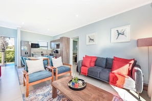 A modern living room with a grey sofa, blue chairs, and a wooden coffee table. - Luxury 2Bed Apartment  Minutes from Sandton (Sandton)