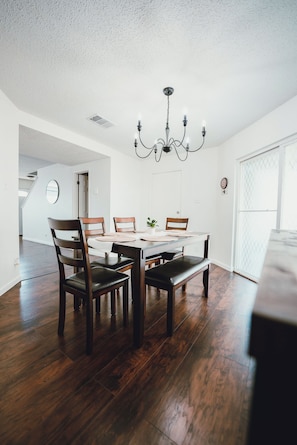 Un coin repas avec une table en bois, des chaises et un lustre.
