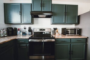 A kitchen with teal cabinets, a stainless steel stove, a microwave, and a coffee maker. - Lovely 3br/2.5ba Home Six Flags/La Cantera/USAA/UTSA (San Antonio)